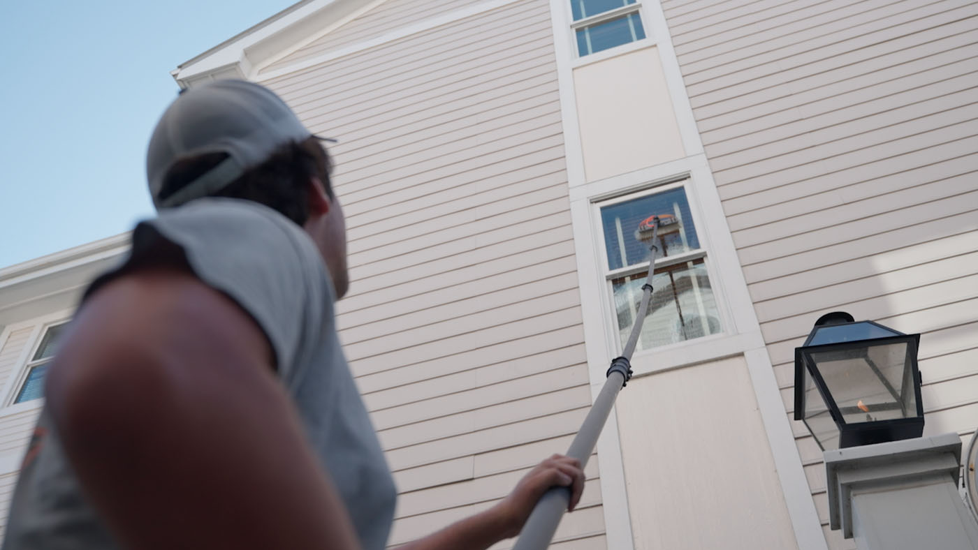 A Window Ninjas window technician cleaning a second story window. 